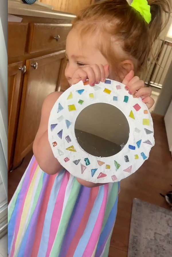 A young girl showing her own mosaic mirror creation with Sculpd kids mosaic kit